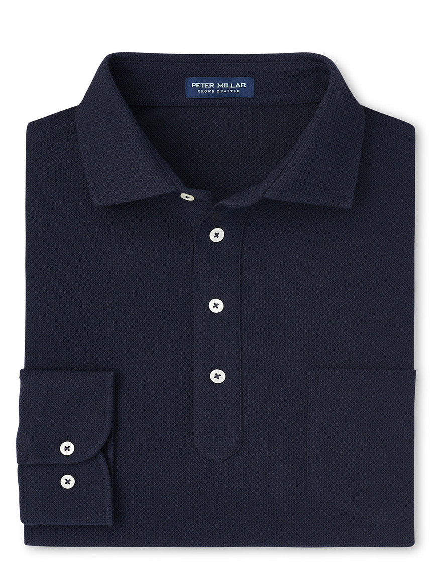 A folded Peter Millar Ramble Long-Sleeve Polo in navy showcases a tailored fit. It features white buttons, a front pocket, and the Peter Millar label on the inside collar. Crafted from a cotton and cashmere blend, this luxurious polo offers both comfort and style.