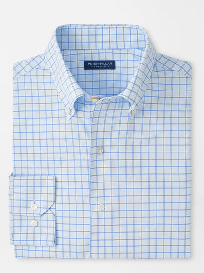 A folded light blue Peter Millar Rampart Performance Poplin Sport Shirt in Blue Brisk features a white and blue checkered pattern and buttoned collar, labeled "Peter Millar.