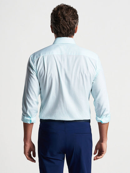 Man standing with his back to the camera, wearing a Peter Millar Renato Cotton Sport Shirt in Iced Aqua and dark blue cotton twill trousers.