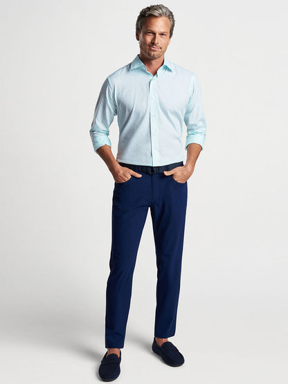 Man posing in a Peter Millar Renato Cotton Sport Shirt in Iced Aqua, navy pants, and dark loafers against a neutral background.