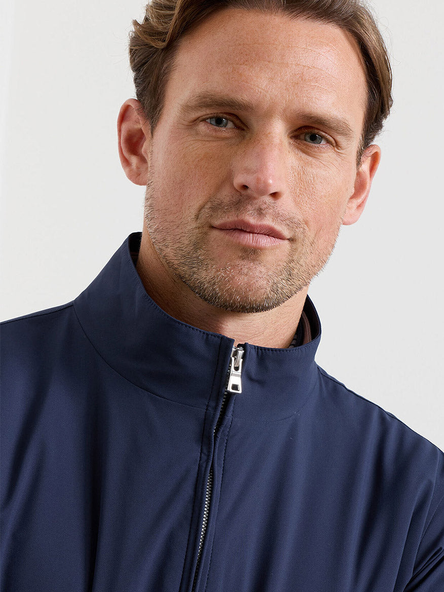 A man with light brown hair and light facial hair models the Peter Millar Ryder 3-in-1 Jacket in Navy, facing the camera against a plain background.
