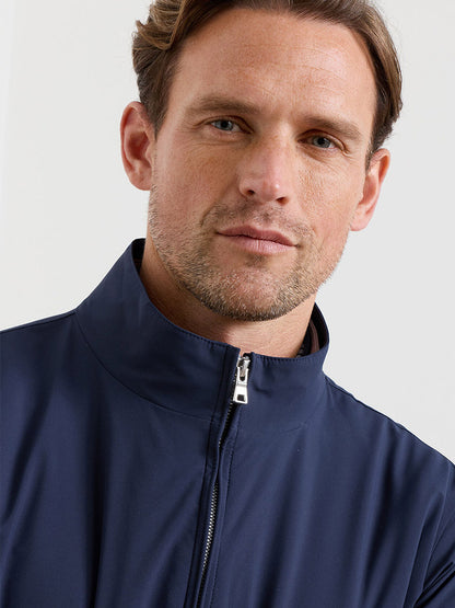 A man with light brown hair and light facial hair models the Peter Millar Ryder 3-in-1 Jacket in Navy, facing the camera against a plain background.