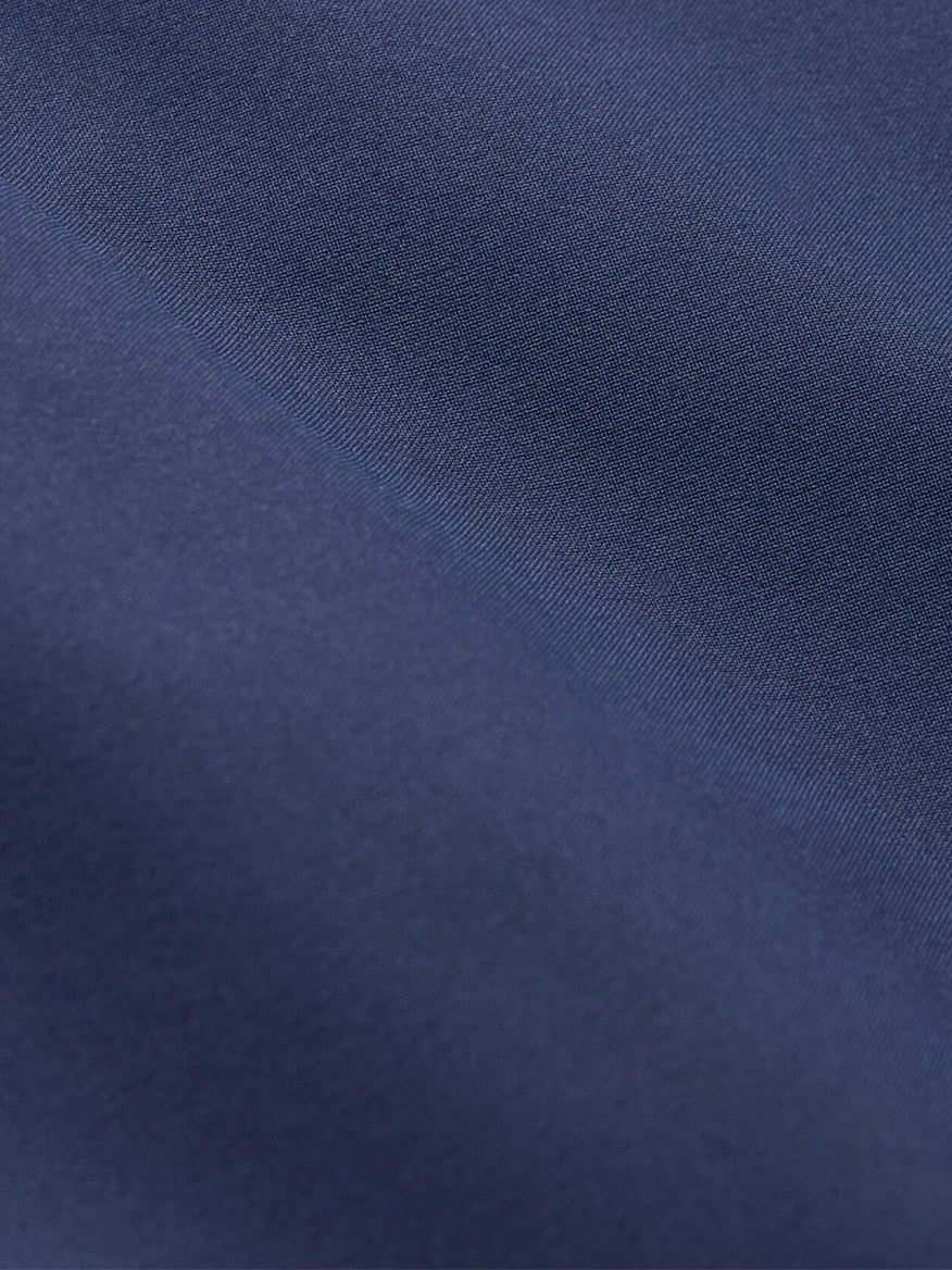 Close-up of the Peter Millar Ryder 3-in-1 Jacket in Navy, showing its lightweight performance shell with a smooth, dark blue finish, subtle diagonal texture, and soft lighting.