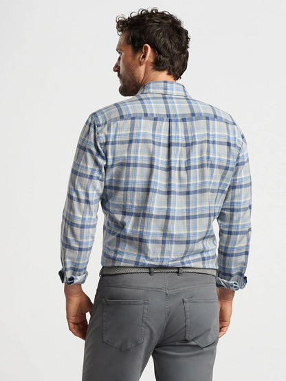 A man with curly hair, viewed from behind, is wearing a Peter Millar Sherbrooke Cotton Sport Shirt in British Grey plaid, paired with gray pants.