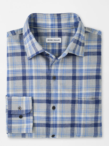 The Peter Millar Sherbrooke Cotton Sport Shirt in British Grey is a classic fit, button-up shirt that features a collar and front pocket. It is crafted from breathable cotton twill for comfort and style, with a folded blue and gray plaid pattern.