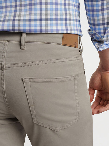 Close-up of a person wearing the Peter Millar Signature Sateen Five-Pocket Pant in Gale Grey, featuring a back pocket and brown leather tag, designed with a comfort waistband for added ease, paired with a blue and white checkered shirt.