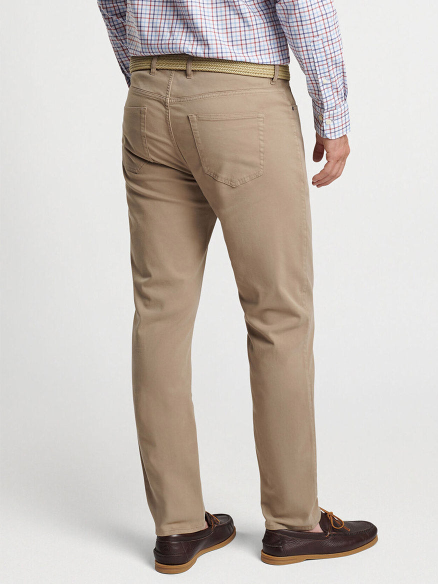 A man wearing Peter Millar Signature Sateen Five-Pocket Pant in Grain, a checkered shirt, and brown loafers is shown from the back.