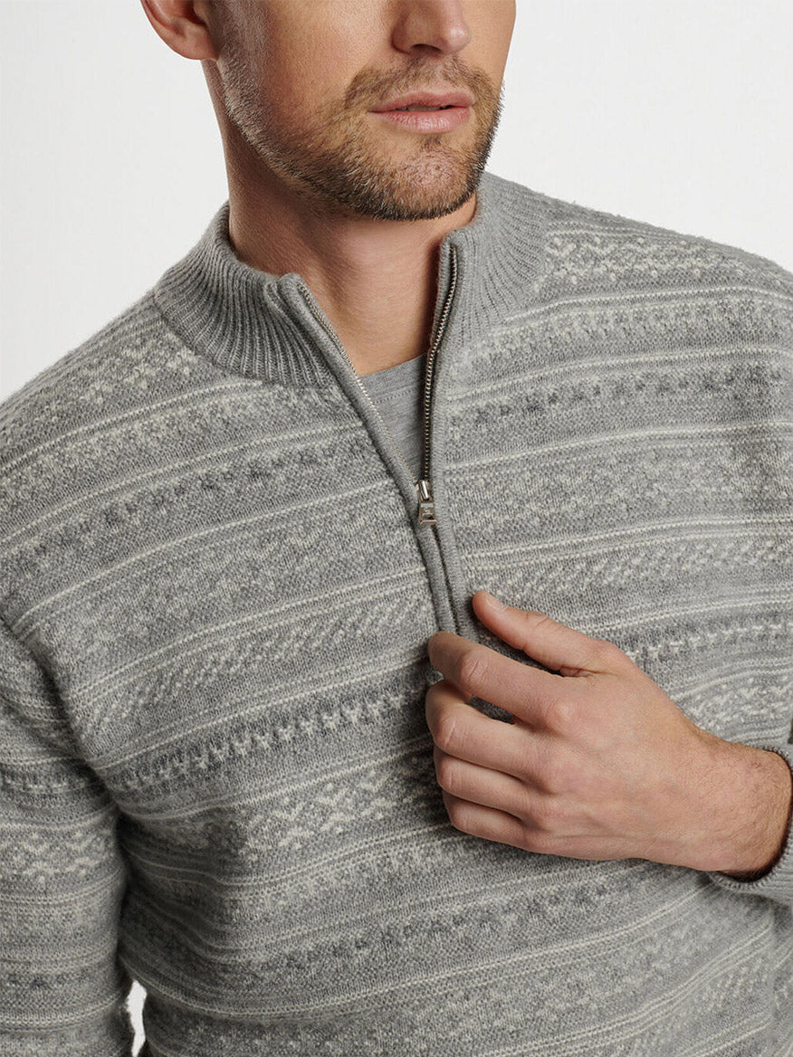 A person wearing a stylish Peter Millar Silverton Jacquard Quarter-Zip in Gale Grey with an intricate Fair Isle pattern.