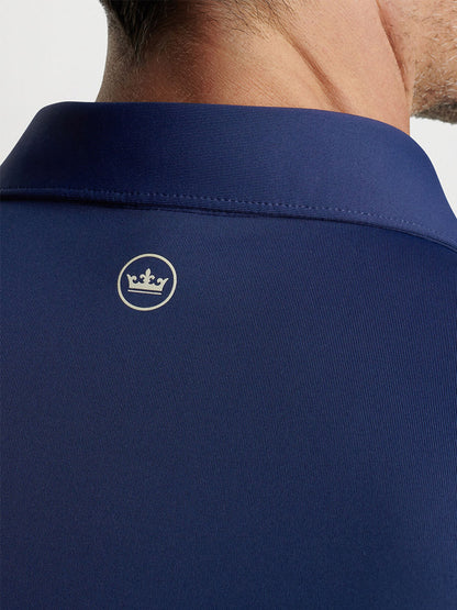 Close-up of a navy blue Peter Millar Solid Performance Jersey Polo with an embroidered crown logo on the back of the collar.