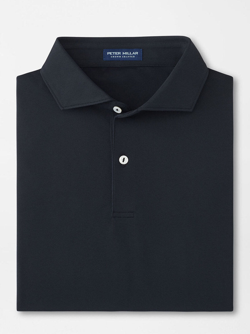 The Peter Millar Soul Performance Mesh Polo in Black is a well-folded, dark-colored shirt with a collar, featuring two mother-of-pearl buttons and an internal neck label.