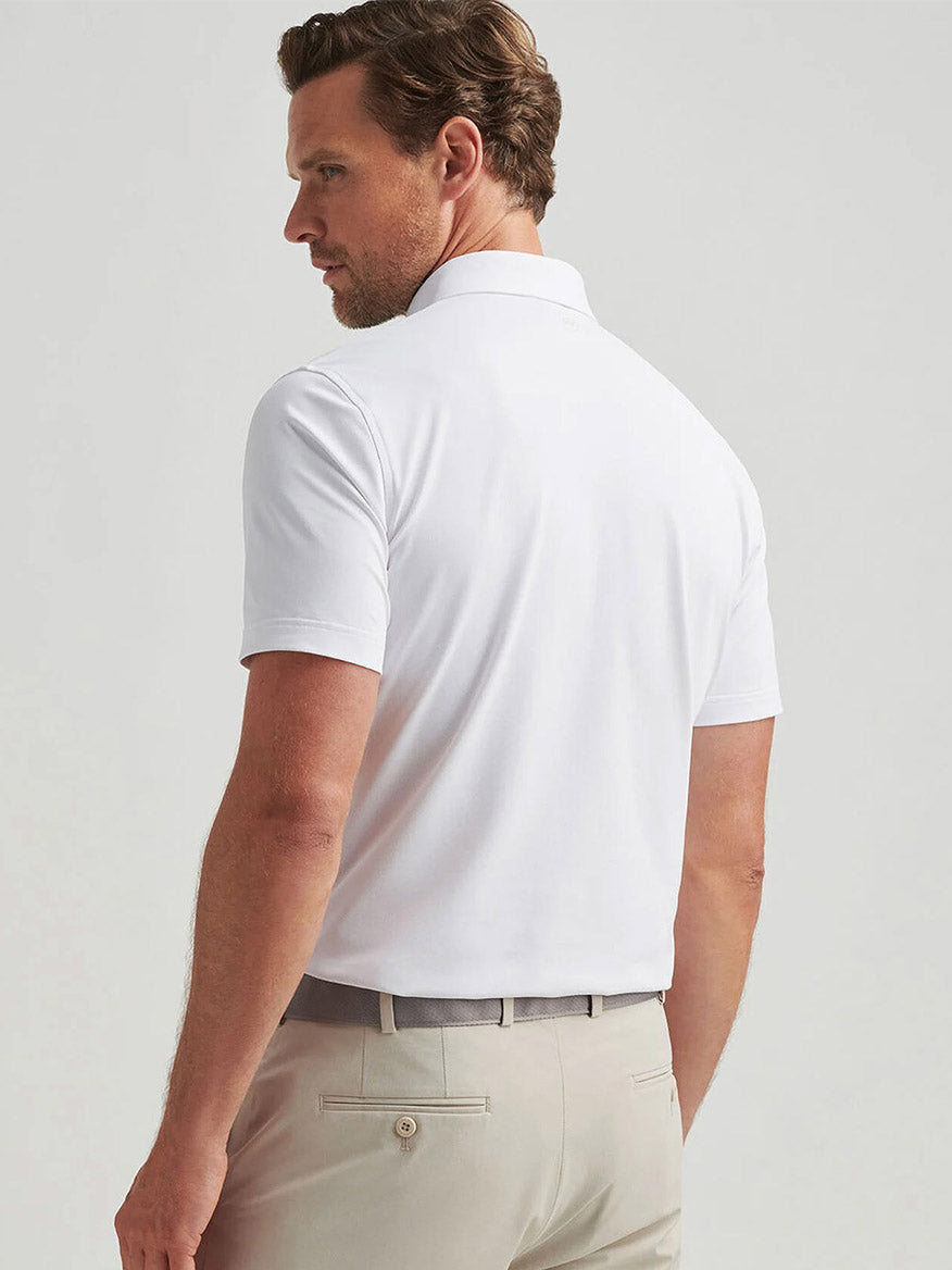 Man shown from the back wearing the Peter Millar Soul Performance Mesh Polo in White and light beige pants, standing against a plain light background.