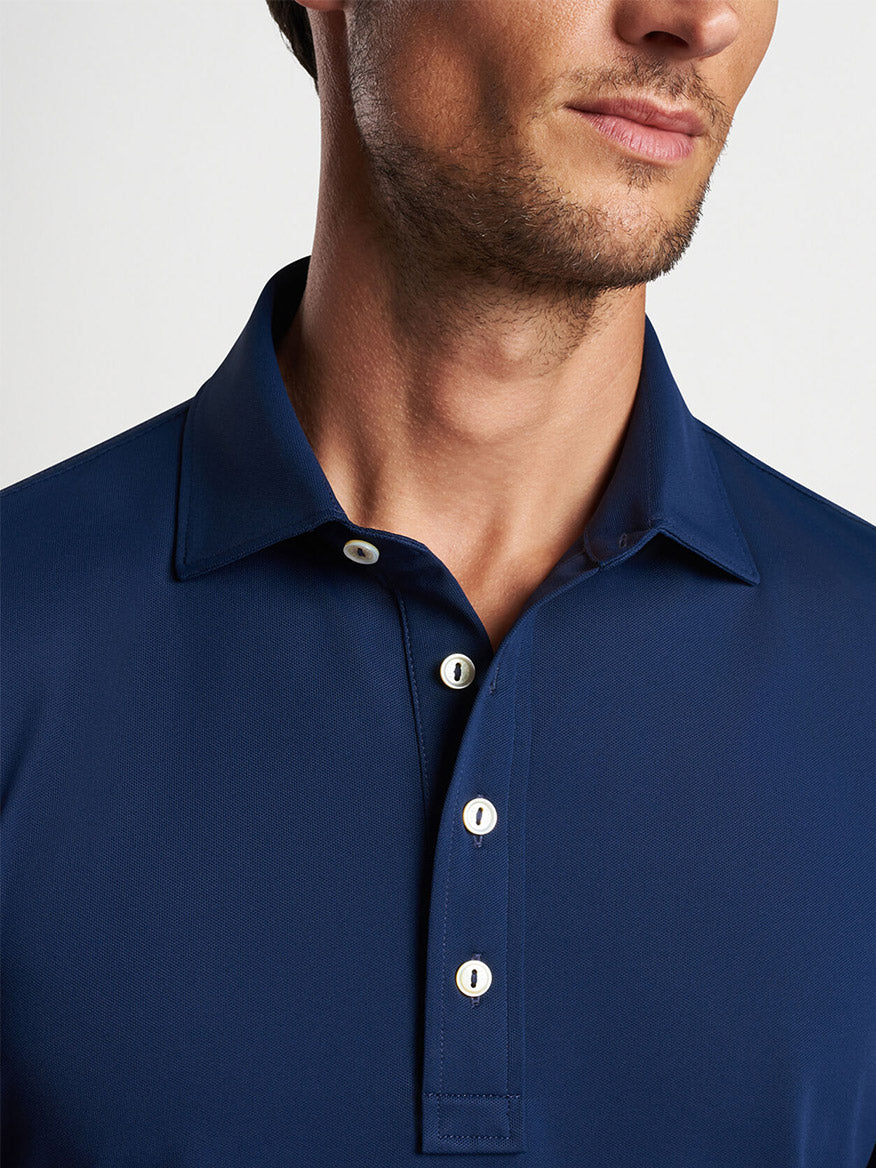 Close-up of a man wearing a Peter Millar Soul Performance Mesh Polo in Navy with four-way stretch.