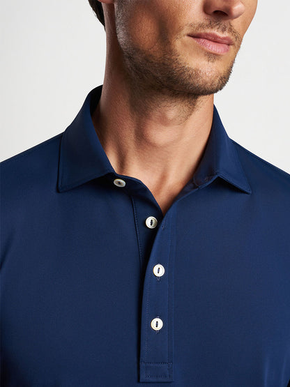 Close-up of a man wearing a Peter Millar Soul Performance Mesh Polo in Navy with four-way stretch.
