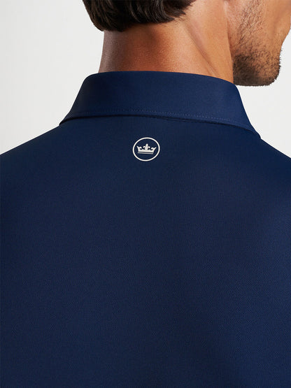 Close-up of a man wearing a Peter Millar Soul Performance Mesh Polo in Navy with a logo on the back of the collar, featuring wicking mesh fabric.