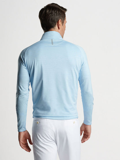 A man seen from behind wearing a Peter Millar Stealth Performance Quarter-Zip in Blue Frost and white pants.
