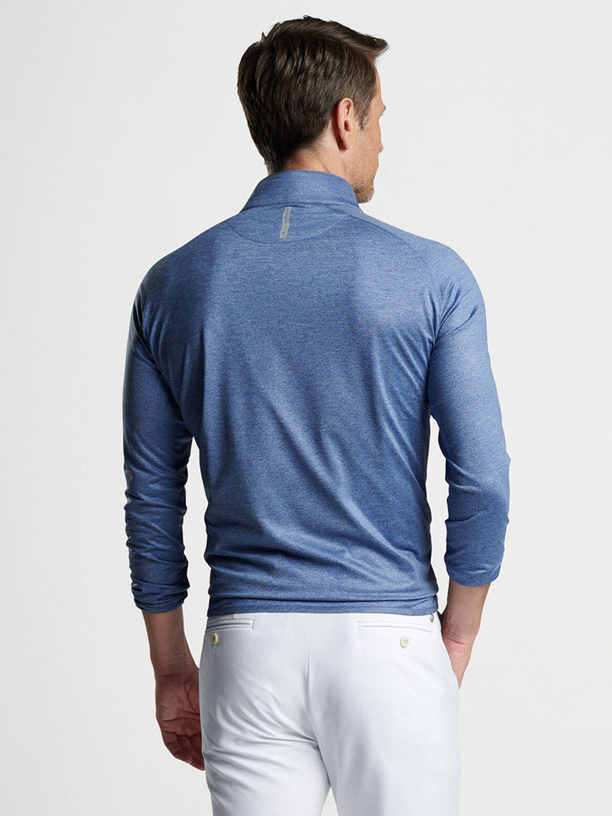 A man viewed from behind wearing a Peter Millar Stealth Performance Quarter-Zip in Blue Pearl and white pants.