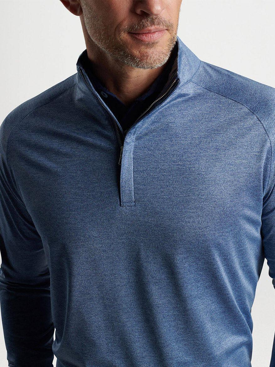 Man wearing a Peter Millar Stealth Performance Quarter-Zip in Blue Pearl with UPF 50+ sun protection.