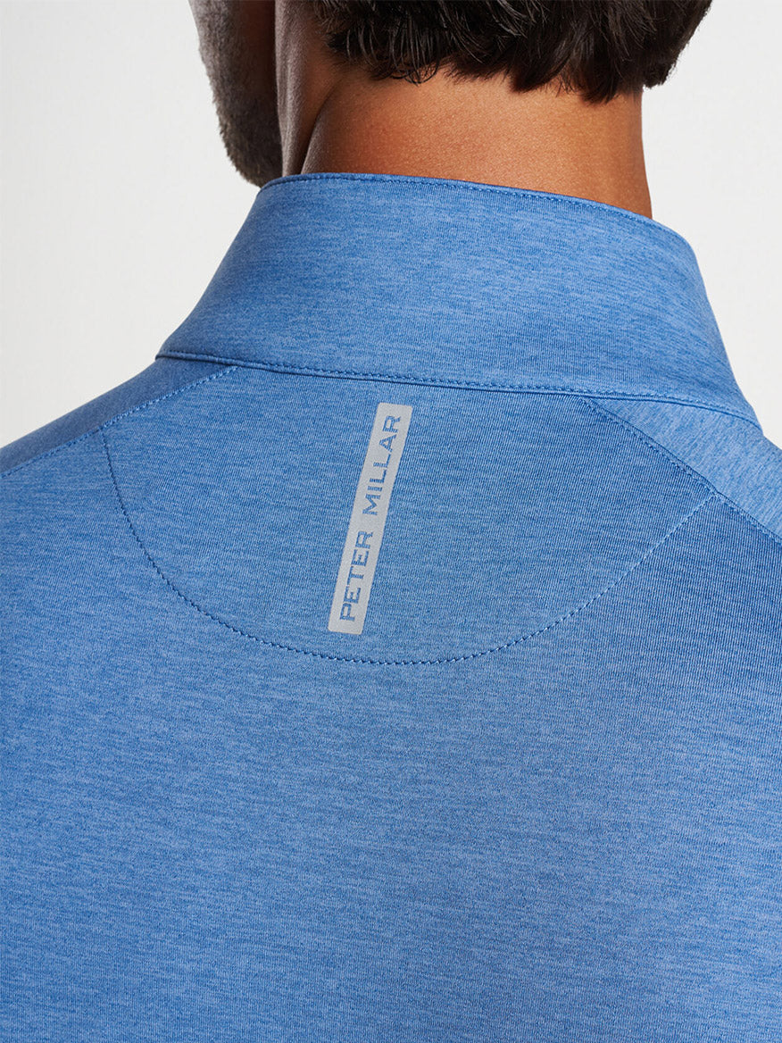 Close-up of the back of a blue, Peter Millar Stealth Performance Quarter-Zip in Cascade Blue with a "peter millar" label.