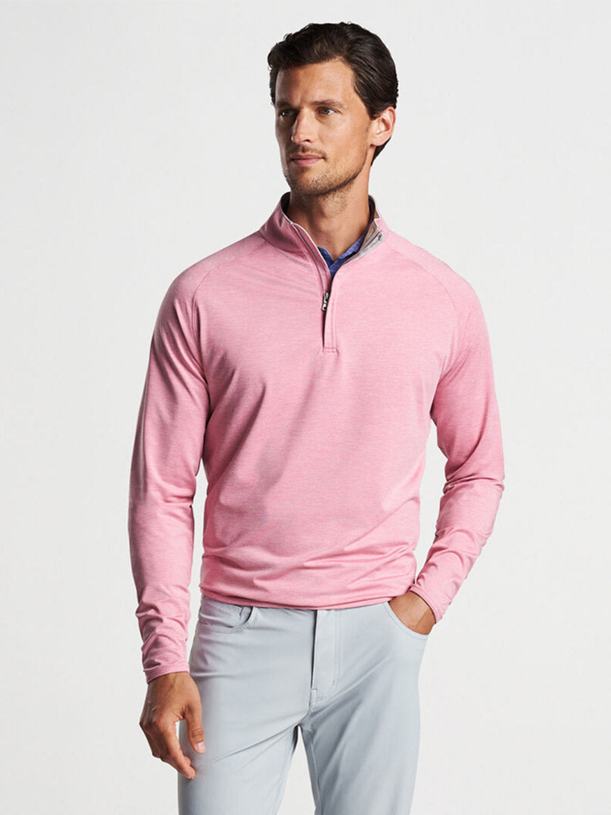 A man wearing a Peter Millar Stealth Performance Quarter-Zip in Spring Blossom with UPF 50+ sun protection and light gray pants.