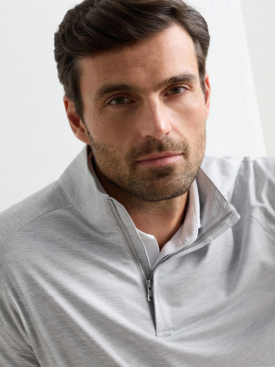 A man with short dark hair and a trimmed beard wears the Peter Millar Stealth Stripe Performance Quarter-Zip in Gale Grey, looking directly at the camera.