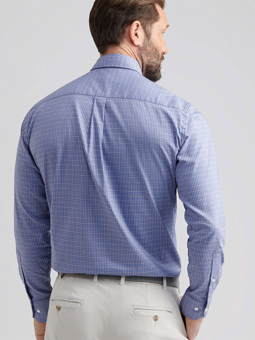 A man is shown from behind wearing a Peter Millar Stowe Crown Lite Cotton-Stretch Sport Shirt in Deep Violet and light-colored trousers with a dark belt.