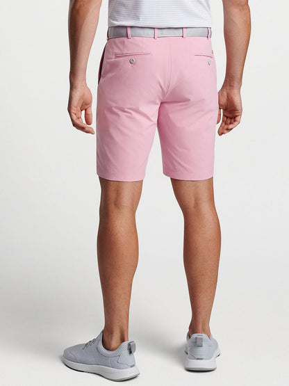 A person standing wearing Peter Millar Surge Performance Short in Spring Blossom and gray sneakers.
