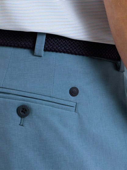 Close-up of a person wearing the Peter Millar Surge Performance Short in Storm, featuring four-way stretch and a back pocket, styled with a dark braided belt and a white shirt with thin horizontal stripes.