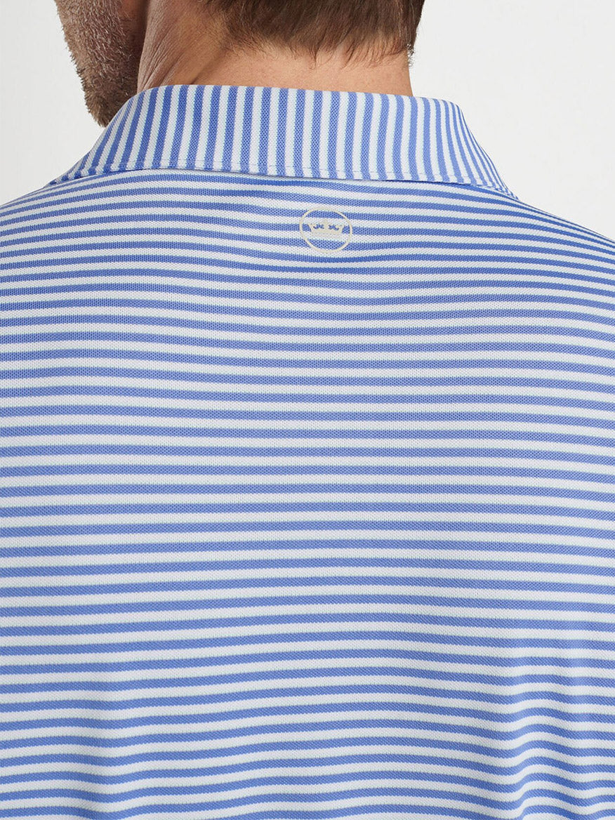 A close-up shows a person wearing the Peter Millar Tempo Performance Mesh Polo in Elixir, a blue and white striped collared shirt with four-way stretch fabric and a small logo at the nape.