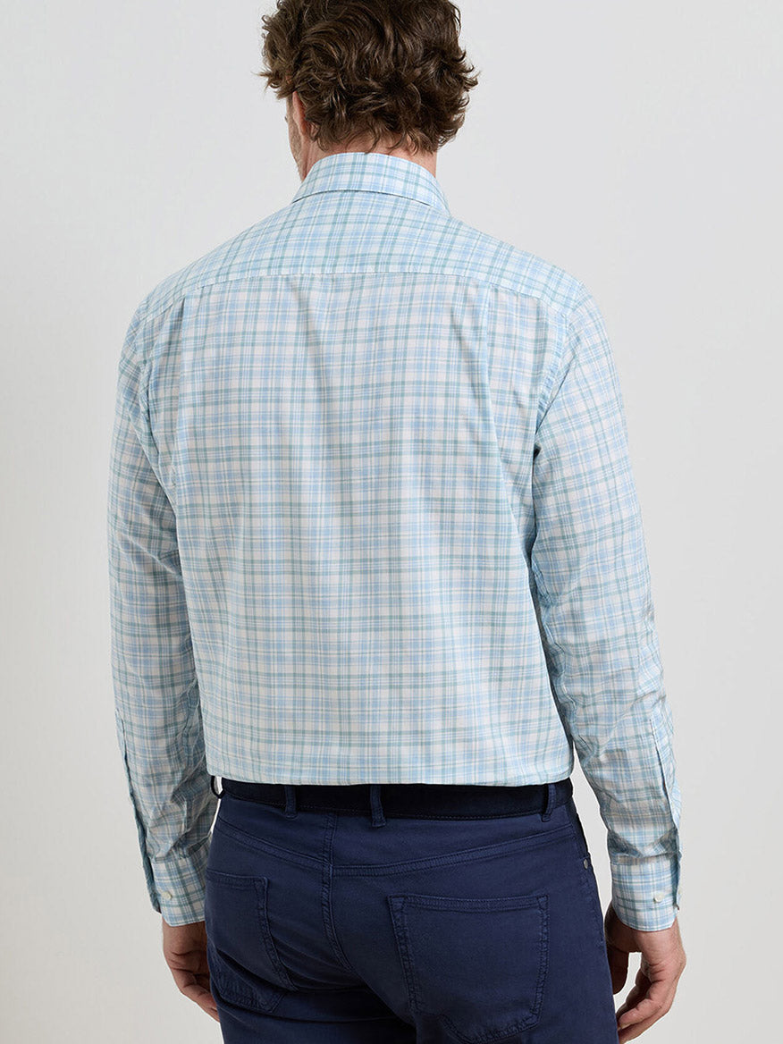 A man is shown from the back against a plain background wearing the Peter Millar Tropea Italian Poplin Sport Shirt in Light Willow and navy blue pants.