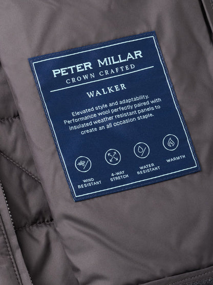Close-up of the Peter Millar Walker Hybrid Jacket in Iridium label, highlighting features such as wind resistance, 4-way stretch, water resistance, and warmth, with descriptive text on a navy patch.