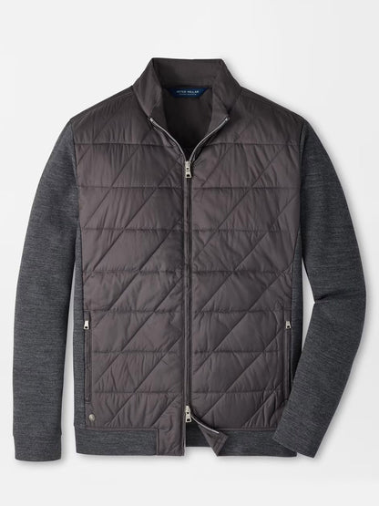 The Peter Millar Walker Hybrid Jacket in Iridium features a gray quilted design with a zip front, stand collar, and knit long sleeves. Shown on a white background, this stylish and versatile water-resistant jacket is perfect for unpredictable weather.