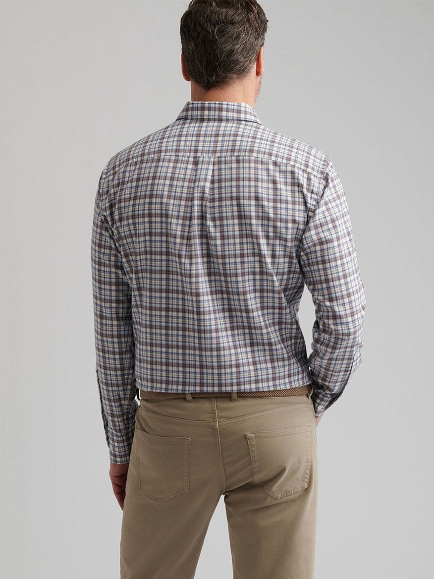 A man faces away, wearing a Peter Millar Waynesville Performance Flannel Sport Shirt in Winter Ivory and tan pants, set against a plain light gray background.