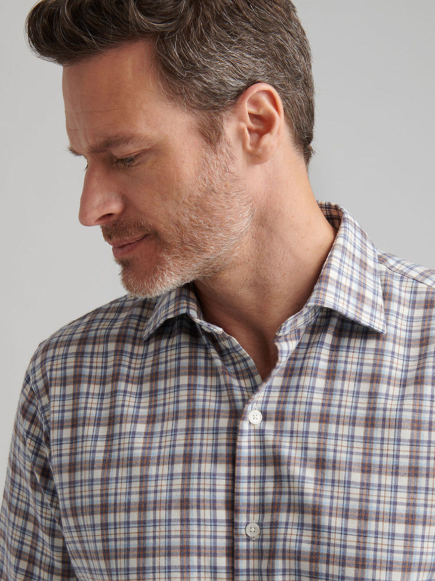 A man with short brown hair and a beard wears the Peter Millar Waynesville Performance Flannel Sport Shirt in Winter Ivory, looking down and to the side against a plain background.