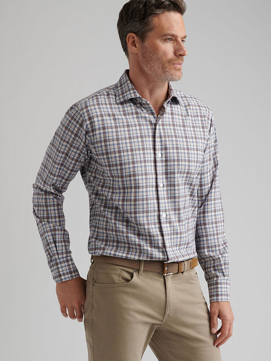 Man wearing a Peter Millar Waynesville Performance Flannel Sport Shirt in Winter Ivory and khaki pants, standing with one hand in his pocket, facing left against a plain background.