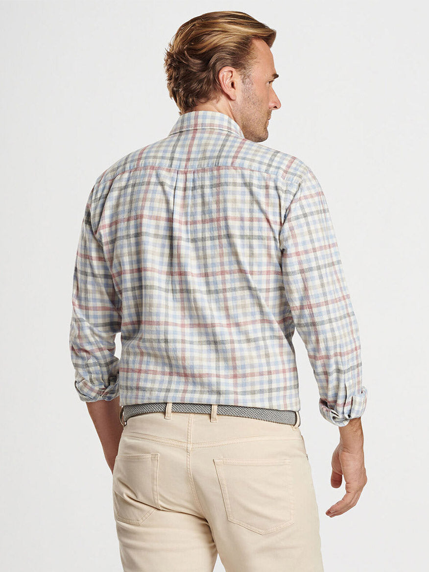 A man in a classic fit, long-sleeve Peter Millar White Rock Cotton Sport Shirt in Winter Ivory and beige pants is shown from the back.