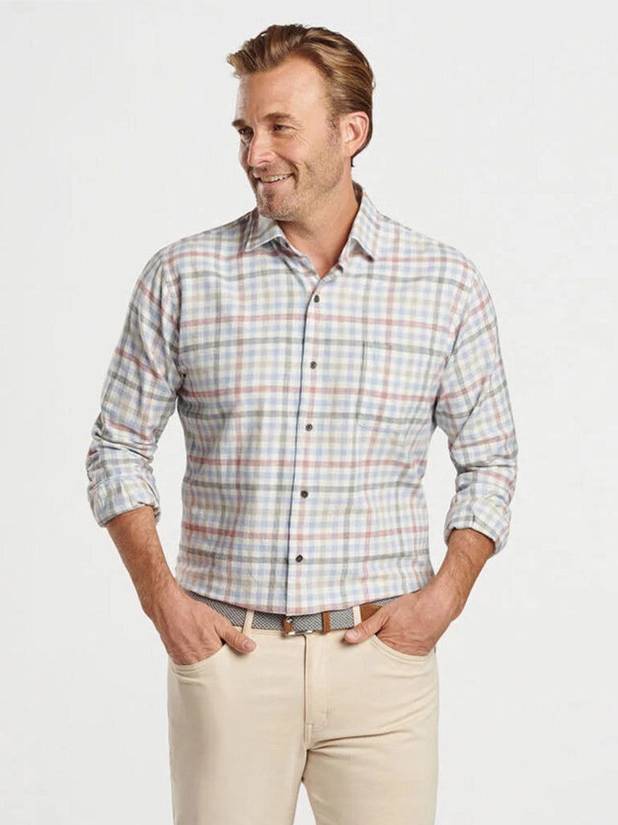 A man wearing the Peter Millar White Rock Cotton Sport Shirt in Winter Ivory and beige pants stands with hands in pockets, smiling against a plain background.