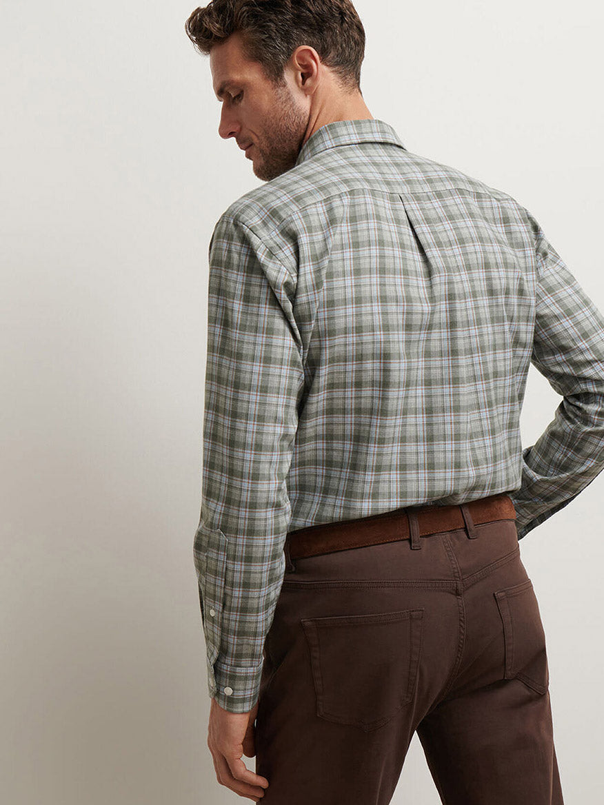 A man wearing a green Peter Millar Whitecap Performance Flannel Sport Shirt in Basil and brown pants stands facing away from the camera against a plain background.