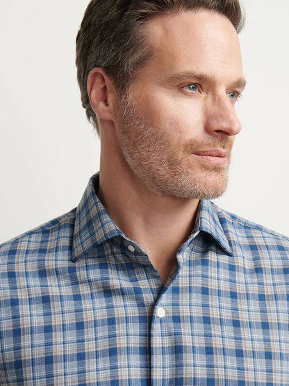 Man with short brown hair and light stubble wears a Peter Millar Whitecap Performance Flannel Sport Shirt in Blue Haze, looking off to the side against a neutral background.