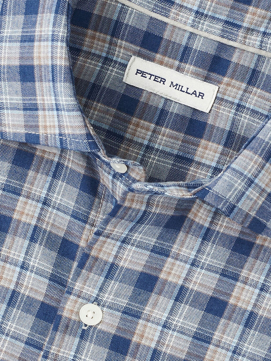 Close-up of the Peter Millar Whitecap Performance Flannel Sport Shirt in Blue Haze, featuring a blue, white, and beige plaid pattern and an interior collar label.