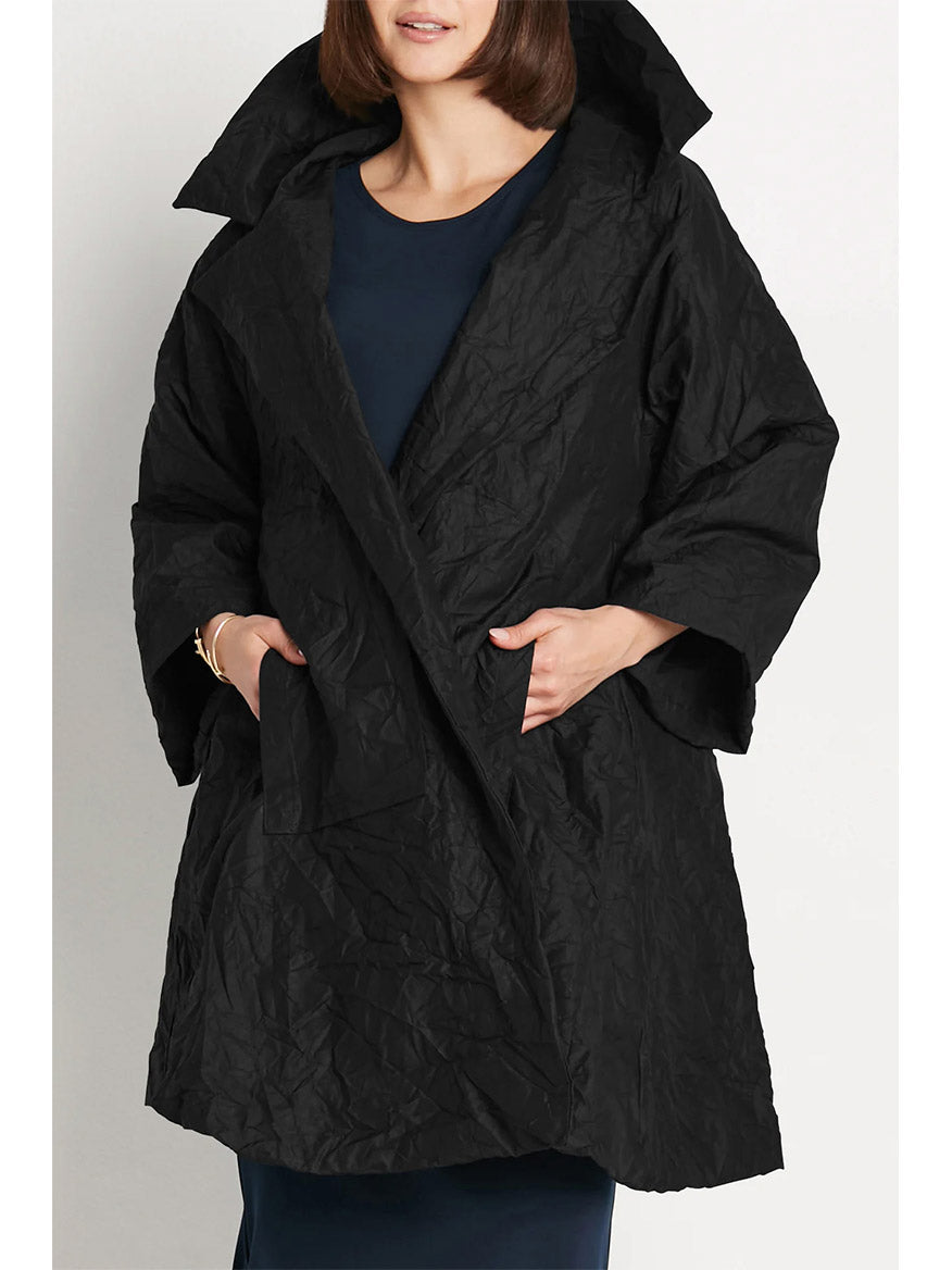 Wearing a stylish Planet by Lauren G Crushed Nylon Emily Coat in Black, featuring a wide collar and pockets, over a dark top, exudes the effortless elegance inspired by "Emily in Paris.