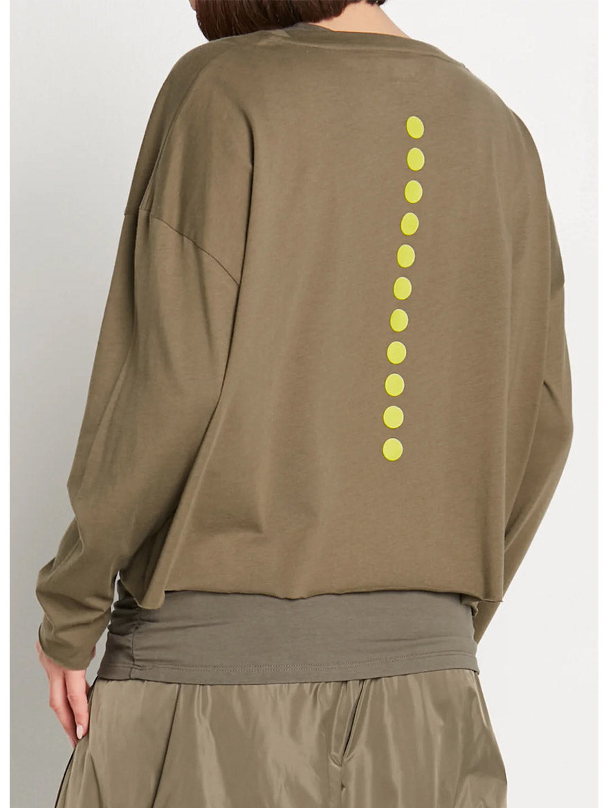 A person wearing the Planet by Lauren G Dot Dot Dot Mini Luxury Boxy Tee in Loden/Guacamole, featuring playful yellow dots arranged vertically on the back, paired with a layered grey Mini Pima Cotton tee undershirt and brown shorts for contemporary comfort.