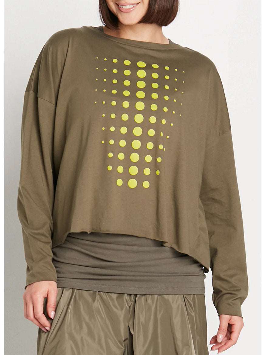 A person wearing the Planet by Lauren G Dot Dot Dot Mini Luxury Boxy Tee in Loden/Guacamole, which features playful dots in a gradient from top to bottom, over a dark gray Mini Pima Cotton tee and khaki pants.