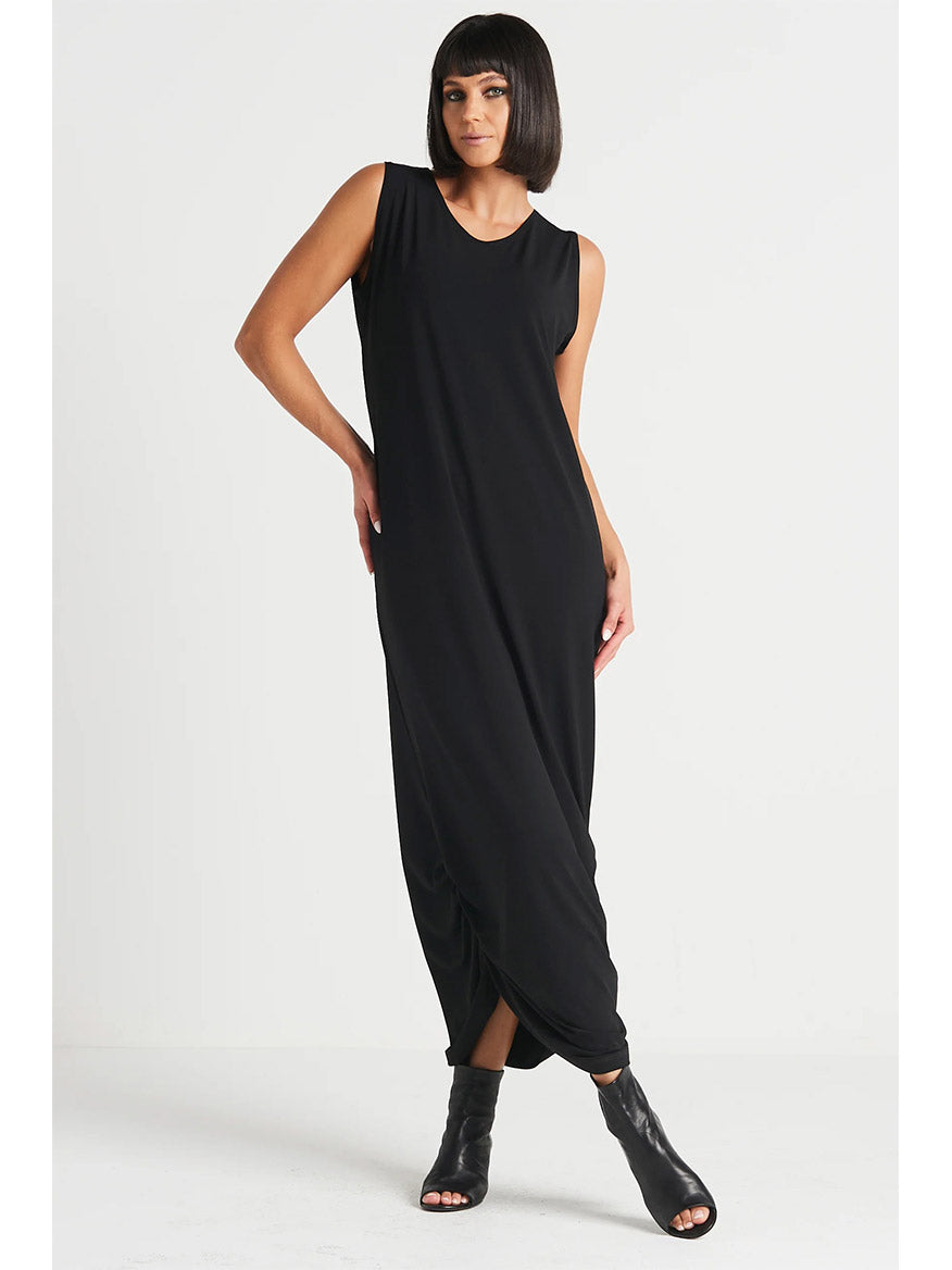 A person with short dark hair is wearing the Planet by Lauren G Matte Jersey Ruched Tank Dress in Black and black ankle boots, standing against a plain white background.