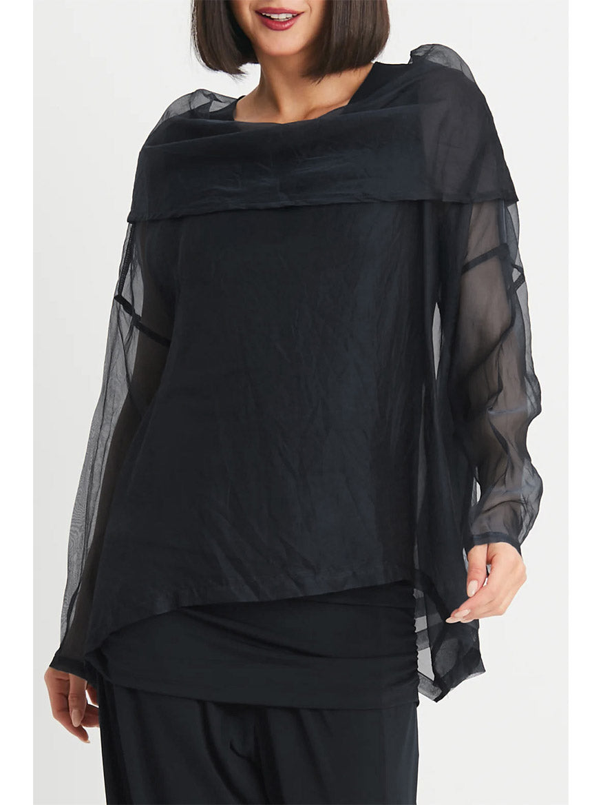 A person wearing the Planet by Lauren G Organza Cowl Neck Top in Black, characterized by its elevated long-sleeve design and asymmetrical hem that adds a feminine touch, stands against a plain white background.