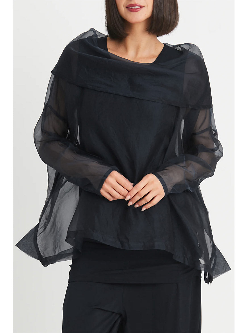 A woman wearing the Planet by Lauren G Organza Cowl Neck Top in Black stands against a plain background with her hands clasped in front of her, adding a sophisticated, feminine touch.