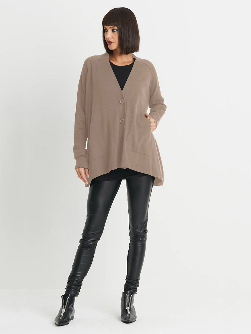 Person standing against a white background, wearing a Planet by Lauren G Varsity Cardigan in Fawn, black top, black leather pants, and black ankle boots. This ultra-soft pima cotton piece is sure to become a wardrobe favorite.