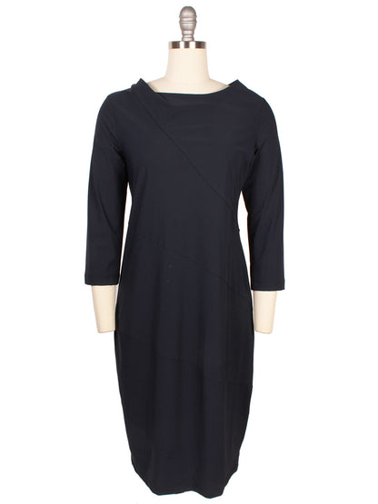 A black dress displayed on a mannequin features three-quarter-length sleeves and falls just above the knee. It boasts a draped neckline and is crafted from Porto Camilla Jersey Dress in Shadow fabric, ensuring both style and comfort.