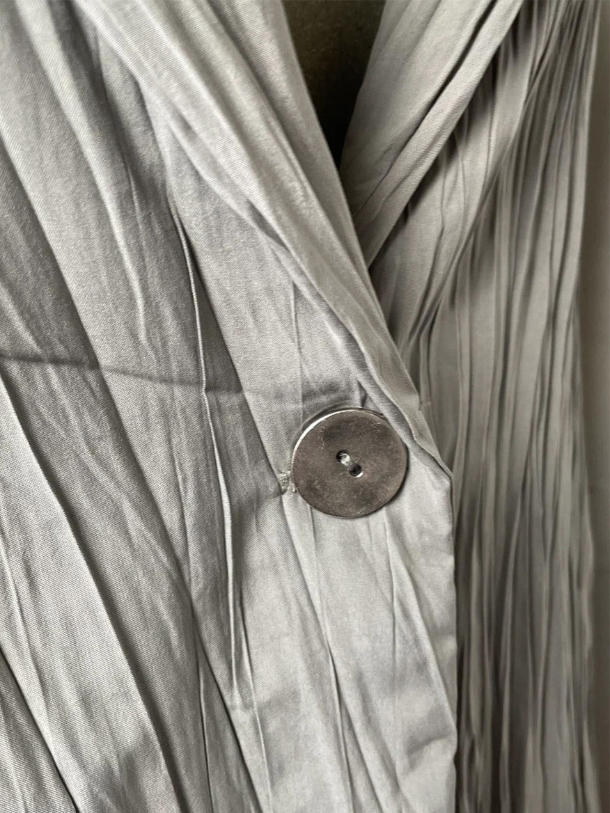 Close-up of a Porto Cicero Pleated Jacket in Dove with a large button and gathered detail.