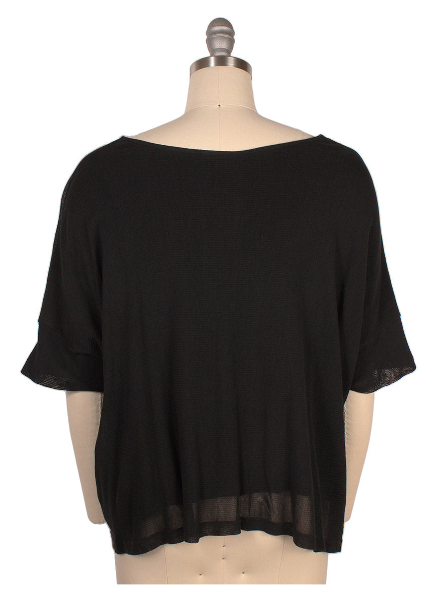 A Porto Tara Mesh Oversize Knit Top in Black displayed on a mannequin, shown from the back. The top has a loose fit and a wide neckline, crafted from lightweight cotton mesh, made in Italy.