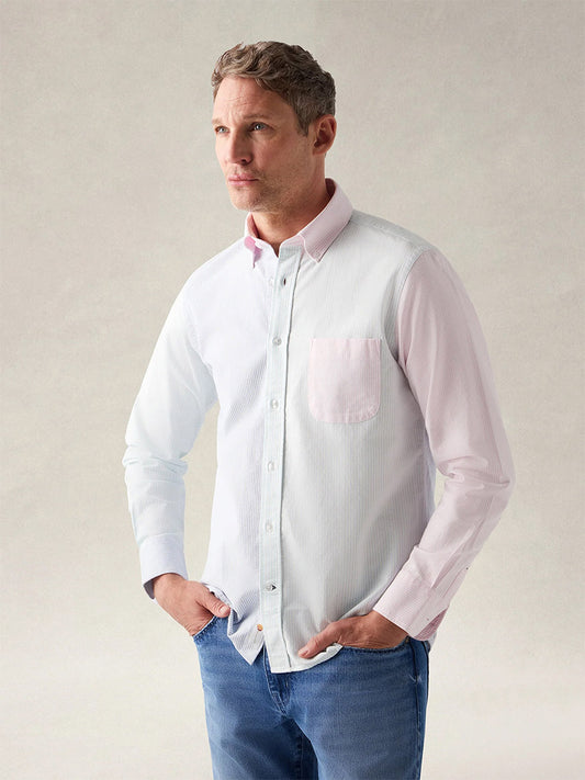 Man standing with hands in pockets, wearing the Robert Talbott Harrison Button Down Fun Stripe Oxford Shirt in Navy/Aqua/Pink, paired with blue jeans against a neutral background.